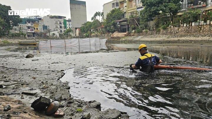 Công nhân ngâm mình dưới làn nước đen ngòm để bơm hút, nạo vét bùn tại hồ điều hòa.