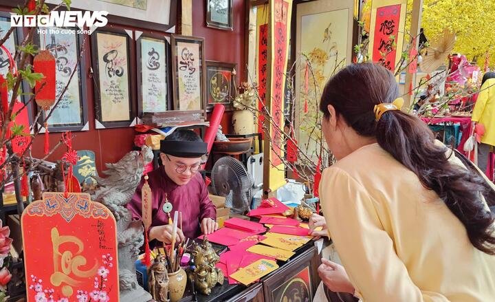 Nghệ nhân thư pháp Võ Minh Mẫn (31 tuổi) lắng nghe câu chuyện của người xin chữ để tìm ra con chữ phù hợp làm “kim chỉ nam” đầu năm.