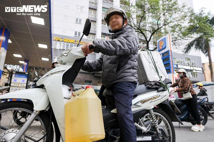 Một người dân Hà Nội mang 2 can đi mua xăng trong chiều 5/3. (Ảnh: Minh Đức)