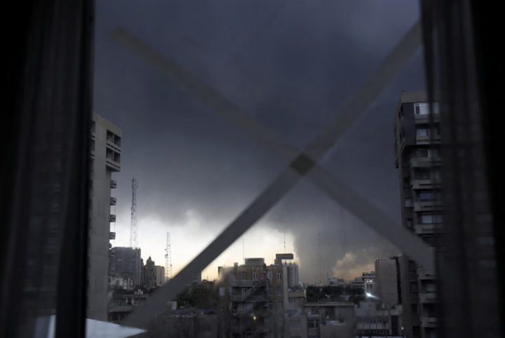 Khói bốc lên sau vụ tấn công nhằm vào các bồn nhiên liệu tại một nhà máy lọc dầu nhìn qua cửa sổ tại Tehran.