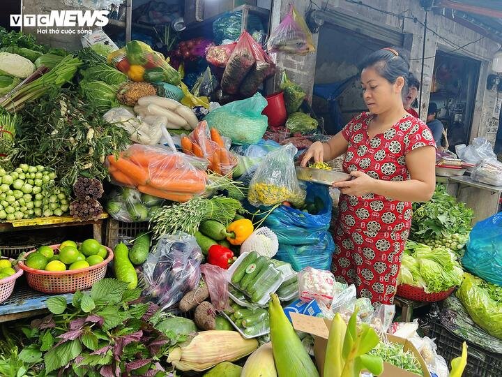 Người dân lựa chọn thực phẩm tại chợ, cân nhắc giá cả trong bối cảnh chi phí sinh hoạt tăng cao.