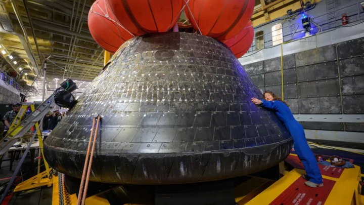 Phi hành gia Christina Koch ôm tàu Orion trong khoang USS John P. Murtha, một ngày sau khi phi hành đoàn Artemis II hạ cánh ngoài khơi California. (Nguồn. NASA)