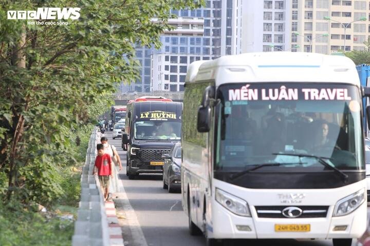 Tại nút giao cao tốc Pháp Vân - Cầu Giẽ và đường Đỗ Mười (phường Yên Sở, Hà Nội), ô tô di chuyển chậm chạp, nhiều người xuống xe khách đi bộ để nhanh chóng thoát khỏi cung đường ùn tắc.