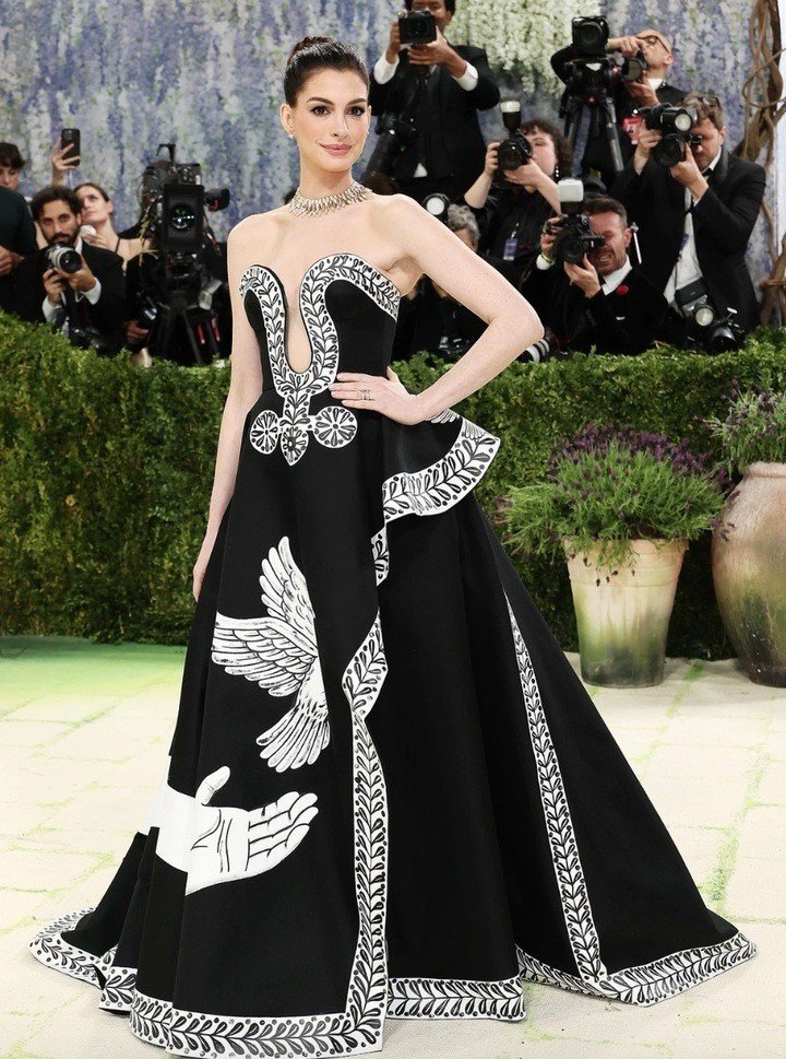 Anne Hathaway thanh lịch trong chiếc váy dạ hội bằng lụa đen, với đường viền cổ xẻ sâu và đường xẻ tà cao. Thiết kế như một bức tranh được tô điểm bằng những họa tiết vẽ tay tinh xảo của Peter McGough.