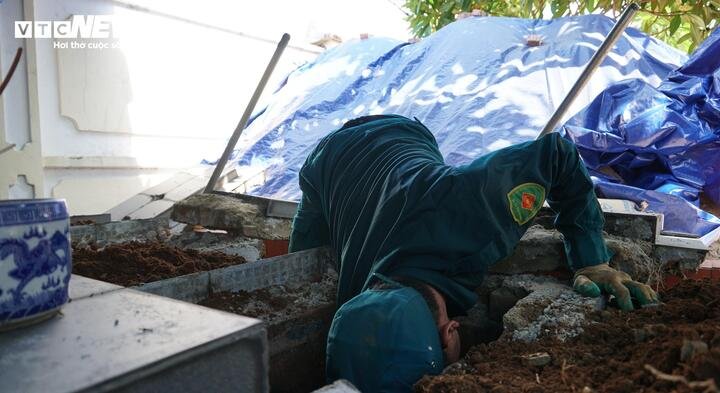 Cán bộ dân quân cúi mình, cẩn thận bốc từng lớp đất sau khi đào đến phần có tiểu quách. (Ảnh: Tiến Thắng)