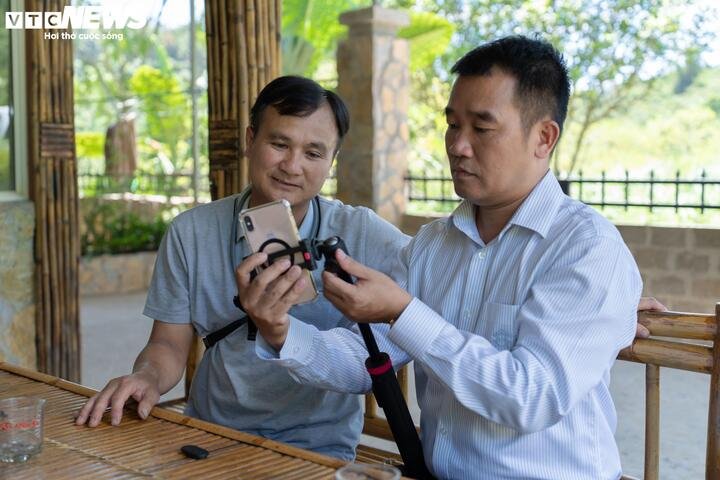 Bí thư Nguyễn Duy Tư (phải) hướng dẫn anh Bùi Văn Khánh sử dụng chân máy, điện thoại và các thiết bị quay, chụp để tự quảng bá homestay, nông sản và hình ảnh địa phương trên mạng xã hội. (Ảnh: Diễm Châu)