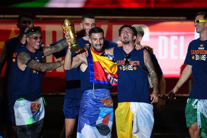 Các cầu thủ mang theo chiếc cúp vàng World Cup, mặc áo in dòng chữ