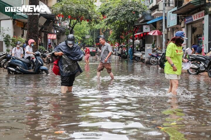 Người dân chật vật đi lại qua khu vực dềnh nước trên phố Hòe Nhai.