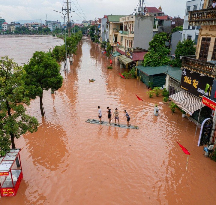 Người dân sống gần sông Kỳ Cùng phải di chuyển bằng thuyền, bè qua những khu vực nước ngập. (Ảnh: Trần Hùng).