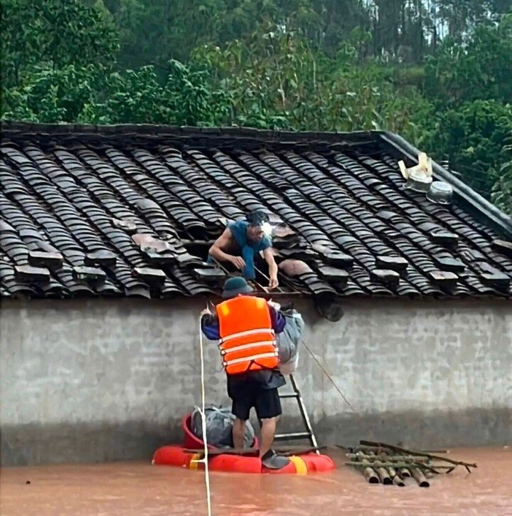 Giữa biển nước mênh mông, người dân phải chui lên mái nhà nhận nhu yếu phẩm.