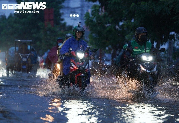 Nước ngập khiến nhiều phương tiện di chuyển chậm. Một số xe máy chết máy, người dân phải xuống xe dắt bộ lên khu vực cao hơn.