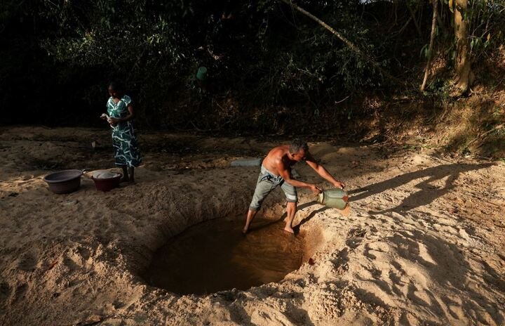 Người dân đào hố trên lòng sông khô cạn để lấy nước tắm ở huyện Ampara, Sri Lanka. (Ảnh: Reuters)