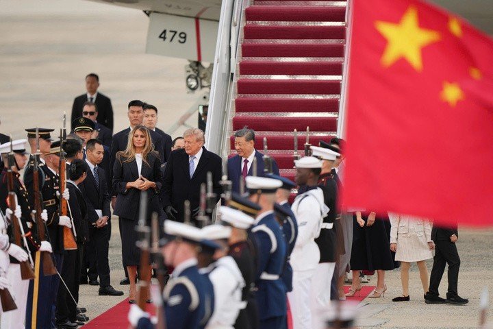 Nhà lãnh đạo Mỹ mặc áo khoác dài và đeo găng tay màu đen đứng cạnh ông Tập trên đường băng trong tiếng nhạc chào mừng của quân nhạc. (Ảnh: AP)