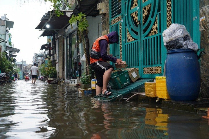 Anh Nguyễn Minh Trường, làm nghề giao hàng, cho biết thay vì chạy xe đến tận cửa nhà như thường ngày, anh phải để xe bên ngoài rồi bê hàng, lội nước vào giao cho khách. “Nước ngập cao, xe máy không chạy vào trong hẻm được nên phải bê hàng lội nước đi từng nhà giao. Bình thường giao hàng khu vực này mất khoảng 1 giờ thì nay phải lội bộ dưới nước, thời gian mất gấp đôi”, anh Trường nói.