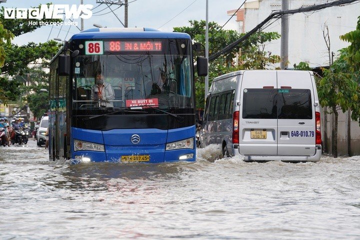 Nước ngập lênh láng trên mặt đường. Mỗi khi xe buýt, ô tô di chuyển nhanh qua khu vực, sóng nước dâng cao, tràn sang hai bên, khiến người đi xe máy chật vật điều khiển phương tiện qua đoạn ngập.