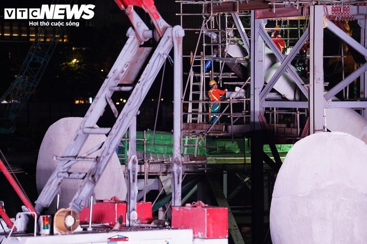 Khoảng 6h, đội thi công tiến hành định vị, hiệu chỉnh cao độ và hạ tải nhịp cầu. Đây là bước chuẩn bị trực tiếp cho công đoạn hợp long, bảo đảm kết cấu nhịp chính được đưa vào đúng vị trí để đấu nối với các hạng mục đã hoàn thành.