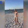 Người đẹp bikini bị đàn chim truy đuổi trên bãi biển